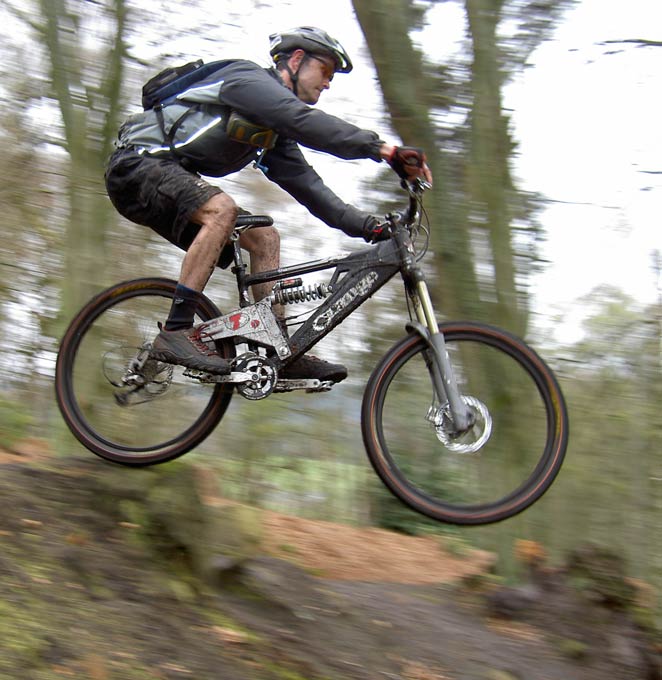 A biker rides down a forested mountain